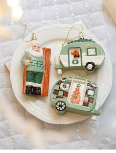 Three-piece Christmas ornaments featuring Santa and camper vans on a white ceramic plate
