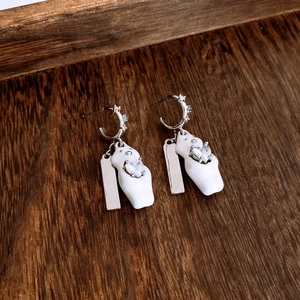 Detail of silver bear earrings with white enamel, heart stone and blue crystal accents