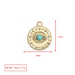 Detail of gold evil eye triangle charm with turquoise bead measuring 21mm by 18mm