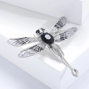Close-up of a silver dragonfly brooch featuring clear rhinestones and black gemstones