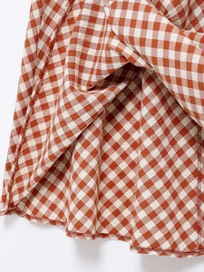 Macro detail of red and white gingham fabric texture with smocked pleats and stitched hem