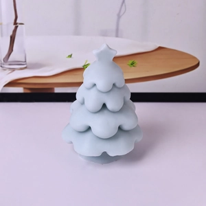 Light blue Christmas tree scented candle with star topper on a cozy home dining table