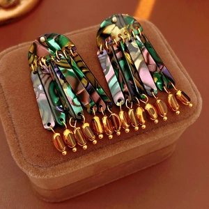 Detail of shell resin tassel earrings with gold chains on brown velvet jewelry box