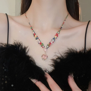 Detail of rose gold V-shaped necklace with colorful gemstones and heart-shaped pink diamond