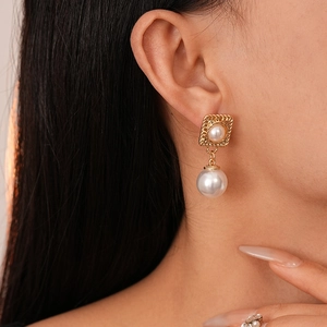 Close-up of vintage French style square gold pearl drop earrings worn by a model