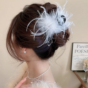 Detail of elegant white feather hair claw clip with rhinestones worn by a model