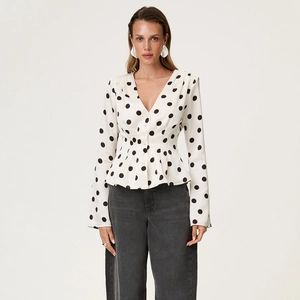 Close-up of white polka dot V-neck blouse with long sleeves and pleated waist detail