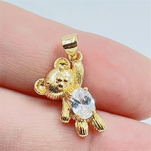 Vue macro d'un pendentif ours doré avec zircon blanc ovale tenu par les doigts