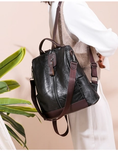 Detail of black soft leather backpack with contrast brown straps shown on a model