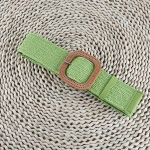 Detail of green woven elastic belt with square straw texture buckle on a round mat