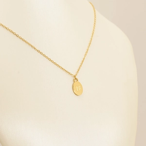 Golden titanium steel oval pendant necklace featuring engraved letter B on model
