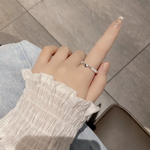 Detail of beaded pearl ring with silver heart pendant on finger for women