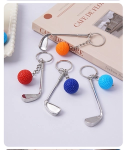 Close-up of mini metal golf club and ball keychains in four colors on a soft background
