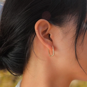 Close-up of elegant U-shaped 18K gold earrings with sparkling pave-set cubic zirconia