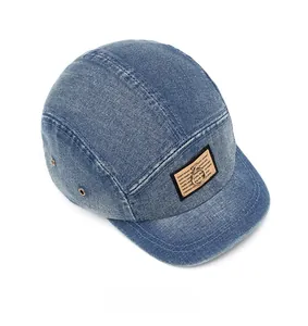 Close-up of washed blue denim five-panel cap with khaki patch and metal eyelet detail