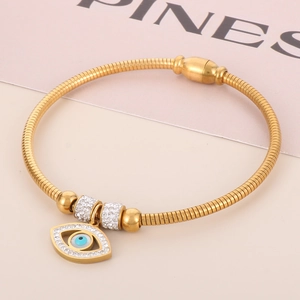Detailed shot of gold snake chain bracelet with evil eye charm and magnetic clasp