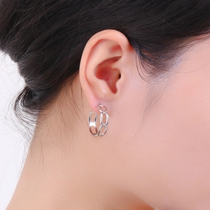 Vue détaillée de boucles d'oreilles argentées à maillons ovales portées par un mannequin