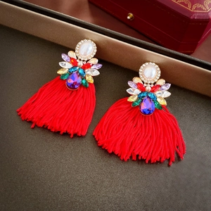 Detail of red tassel earrings with multi-color gemstones and a pearl stud centerpiece