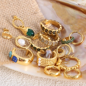 French vintage gold plated earrings set with pearls and gemstones on linen backdrop