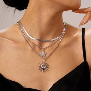 Macro shot of silver layered necklace featuring starfish and vintage sun face pendants
