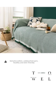 Close-up of green waffle weave cotton sofa cover blanket featuring decorative fringe edges