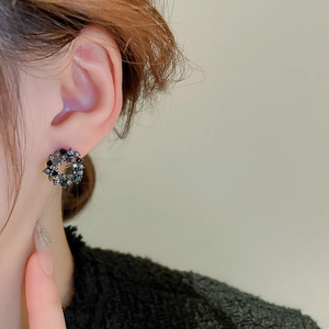 Close-up of a model wearing a small black rhinestone circle geometric stud earring
