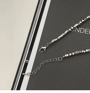 Macro view of silver pearl necklace clasp with adjustable chain on background