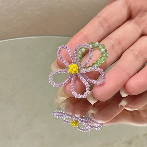 Détail d'une bague fleur en perles cristal violettes avec un cœur jaune central