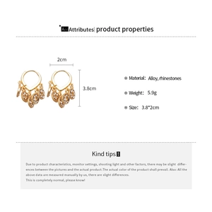 Details von Goldlegierungsohrringen mit Strasssteinen und chinesischem Münzdesign
