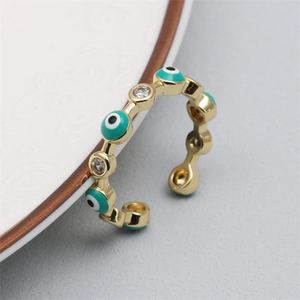 Macro shot of an adjustable gold ring featuring turquoise enamel eye and zircon details