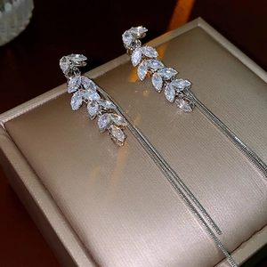 Detailed view of silver wheat chain earrings with marquise crystals on a gift box