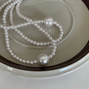 Detailed view of elegant white pearl necklace with two large accent pearls in ceramic dish