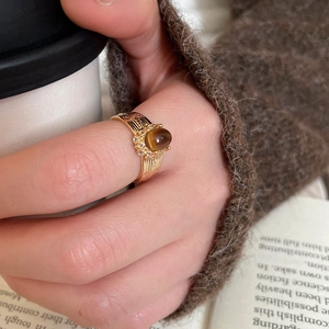 Detailed view of a gold-plated tiger eye ring styled with a sweater and coffee cup