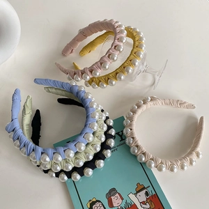 Close-up of colorful woven pearl headbands in various soft pastel shades and fabric textures