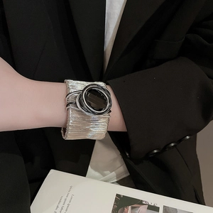 Close-up of a wide silver mesh bracelet featuring a large black oval stone and metal wire