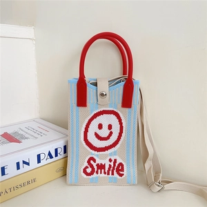 Detail of knitted phone bag featuring a red smile face design and snap button closure