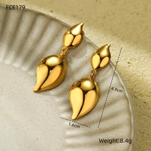 Macro view of gold teardrop earrings with dimensions 4.9cm by 1.6cm on ceramic