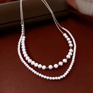 Detail of double-layer necklace with brushed silver metallic beads on leather case