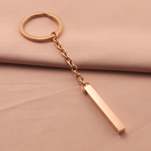 Close-up of rose gold rectangular bar keychain on pink fabric with high-angle view