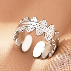 Detail of silver wavy open ring with caviar texture on gold satin background