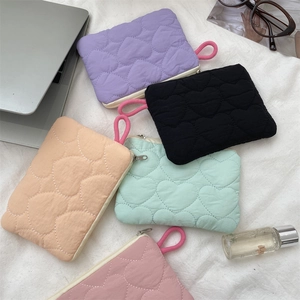 Flat lay of quilted heart mini pouches in multiple pastel colors with daily accessories