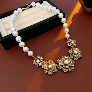 Detail of vintage flower necklace with artificial pearls and gold finish on red background
