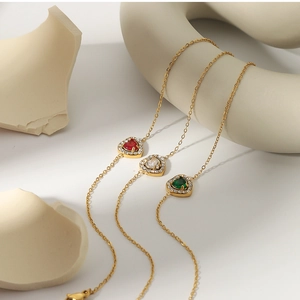 Macro detail of heart-shaped gemstone pendants in red, white and green with gold plating