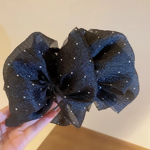 Détail d'une pince à cheveux en tulle noir avec strass argentés et ruban élégant