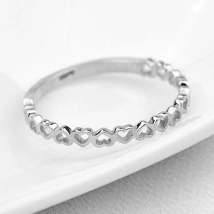 Macro shot of a minimalist silver hollow heart pattern ring band with polished finish