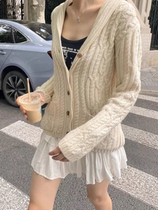 Close-up of beige cable knit cardigan featuring brown buttons and high-quality texture