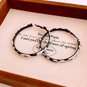 Elegant large hoop earrings with black and white leopard pattern on a soft velvet tray