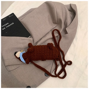 Detailaufnahme der handgefertigten Häkel-Dackeltasche mit blauem Schal auf grauem Sakko
