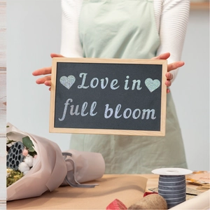 Detail showing Love in full bloom glitter text on a decorative wooden blackboard