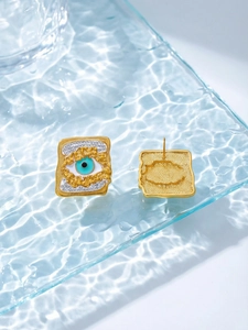 Detailed macro view of square gold Evil Eye earrings featuring blue zircon and lava texture